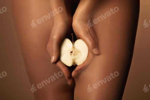 Preview: cropped view of woman in nylon tights holding apple half isolated on brown