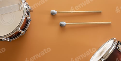 Preview: Drums and drum sticks on a brown background, top view.