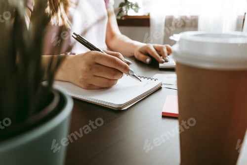 Preview: Close up of a woman writing something on the paper in office