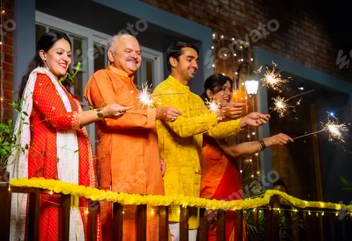 Preview: Enjoying festive sparkles on balcony, joyful Indian family celebrates Diwali in traditional clothing