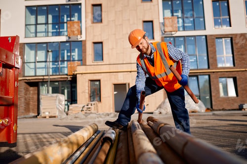 Preview: Construction worker holding pipe on site outdoors