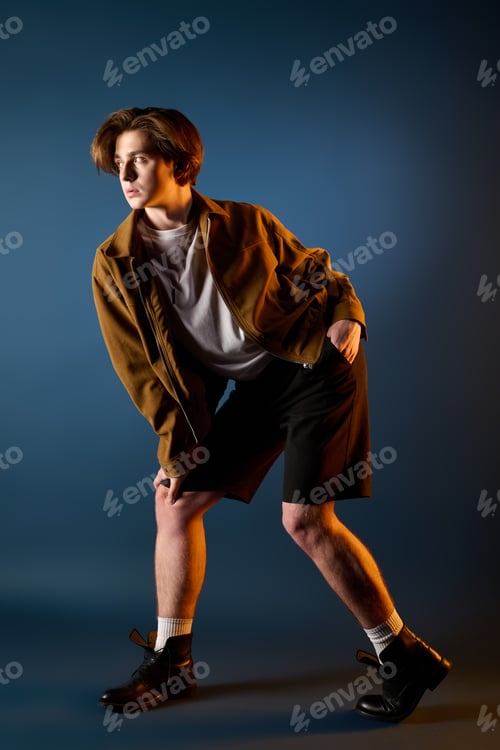 Preview: Young fashionable man striking a dynamic pose against a bold background