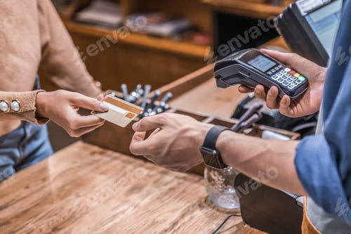 Preview: Male barista holding credit card reader machine with female customer credit card for payment.