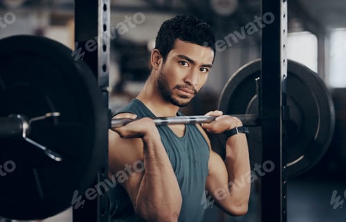 Preview: Portrait of a muscular young man exercising with a barbell in a gym
