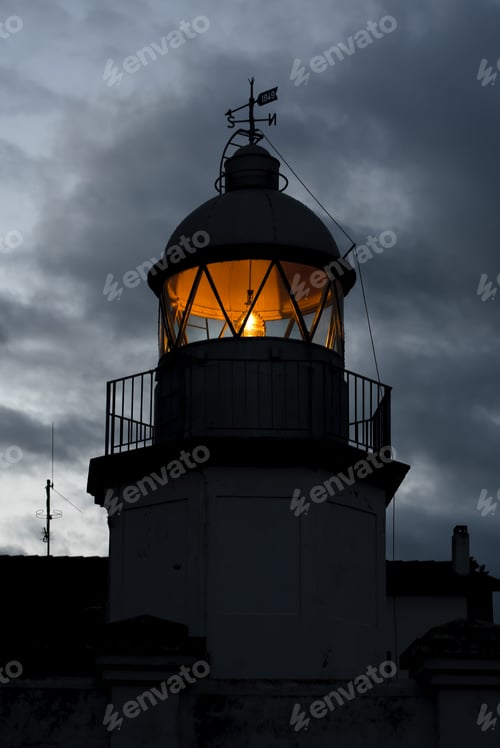 Preview: Shining lighthouse against cloudy sky
