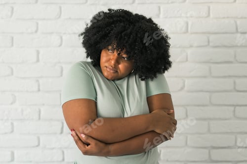 Preview: Portrait of depressed African American woman overthinking while standing brick wall at home
