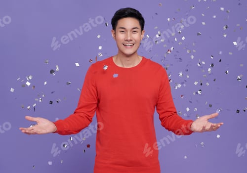 Preview: happy satisfied excited surprised asian man 20s in casual red clothes tossing throwing confetti