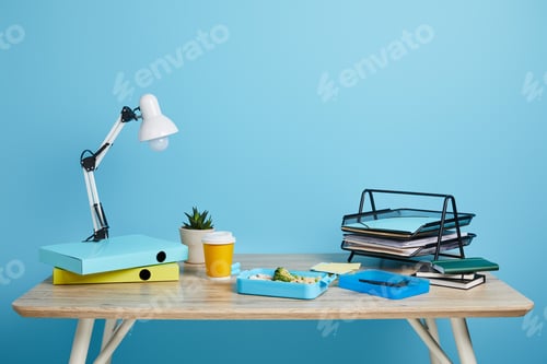 Preview: workspace with lunch box and coffee to go on wooden table on blue background