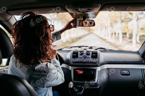 Preview: young beautiful woman driving a van by a path of trees. travel concept, view from inside