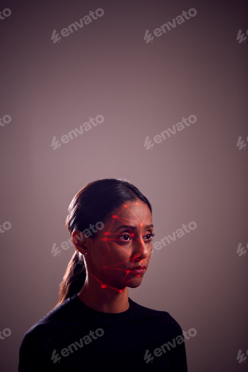 Preview: Facial Recognition Technology Concept As Woman Has Red Grid Projected Onto Face In Studio