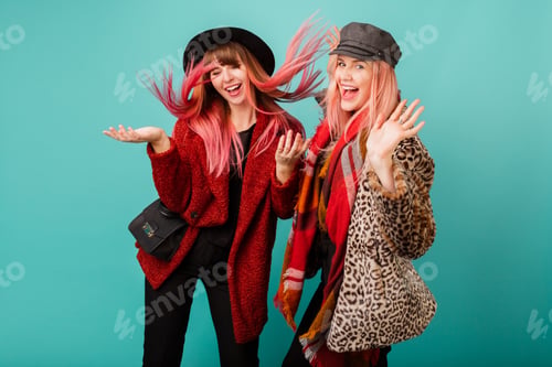 Preview: Two stylish blond women posing in studio on blue turquoise background.