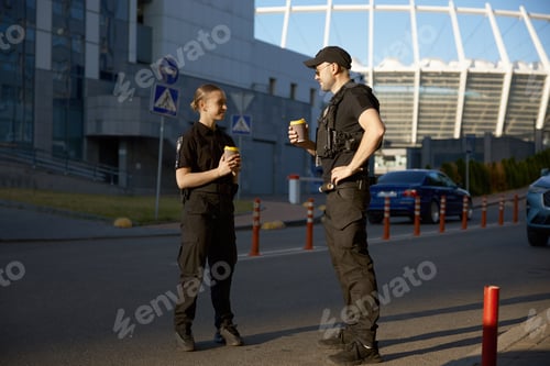 Preview: Cheerful patrol officers talking together drinking coffee having work break
