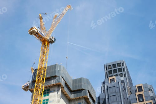 Preview: LONDON - MAY, 2017: Crane and modern buildings under construction against blue sky,