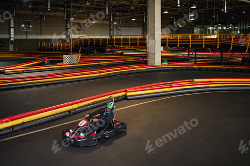 Preview: speed drive, african american man in go-kart on circuit, racing inside of indoor karting track