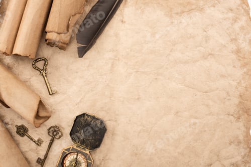 Preview: top view of vintage keys and compass near feather on aged paper