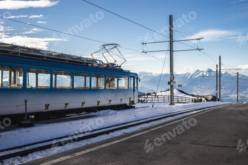 Preview: Blue cogwheel train beside an overhead line during winter under a blue sky