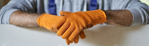 Preview: Close up shot of hands of male builder wearing protective gloves holding drywall while working