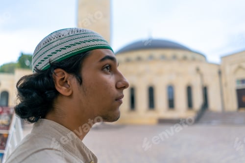 young guy of Arab appearance in a national Muslim headdress against the background of a mosque