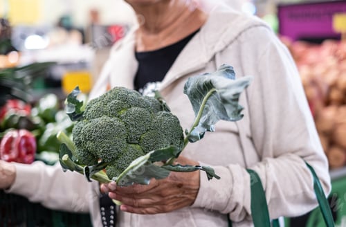Preview: In the fruit and vegetable market, female hands take a head of freshly picked broccoli