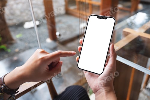 Preview: a woman holding and pointing finger at mobile phone with blank white desktop screen in cafe