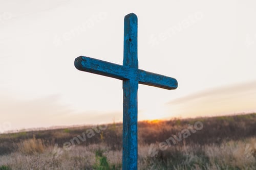Preview: Blue Wooden Cross Standing Amidst Tall Grasses at Sunset