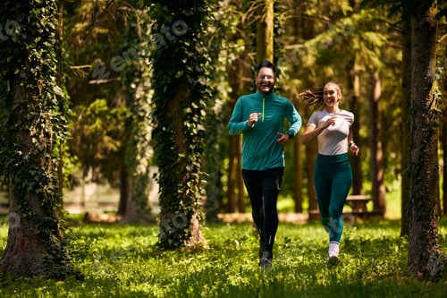 Preview: Happy sports couple jogging through the park.