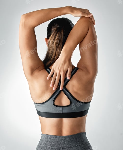 Preview: Studio shot of a sporty young woman stretching her arms against a grey background
