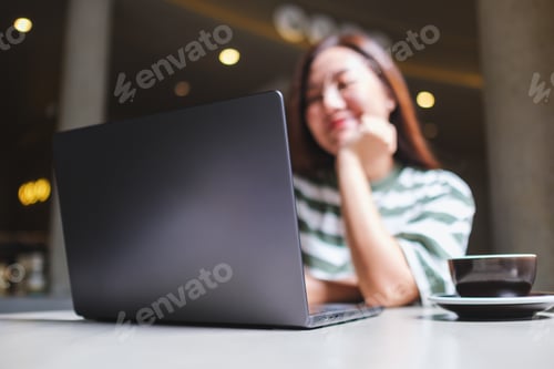 Preview: Blurred image of a woman working on laptop computer in cafe