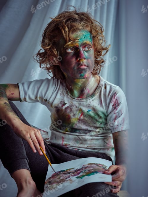 Preview: Boy with painted face looking away and drawing