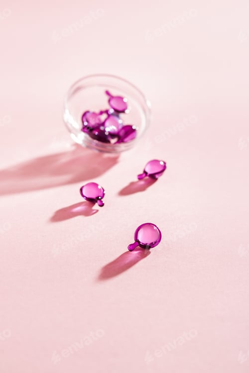 Preview: Vitamin capsules in pink, purple color, closeup on pink background, top view
