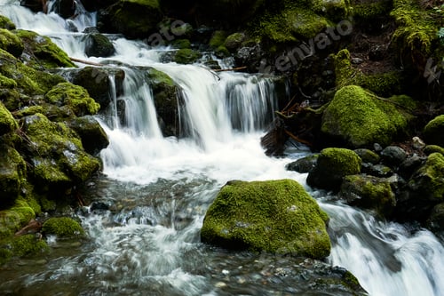 Preview: A beautiful waterfall rushing down a rocky river bed amongst rocks covered in brilliant greeen moss.