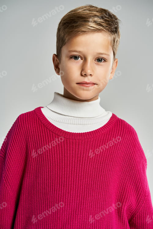 Preview: A child dressed warmly in cozy winter attire with a joyful expression against a plain backdrop