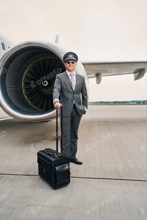 Preview: Pleased young pilot with his baggage posing for the camera