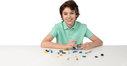 Preview: a young woman sitting at a table with a pile of lego blocks