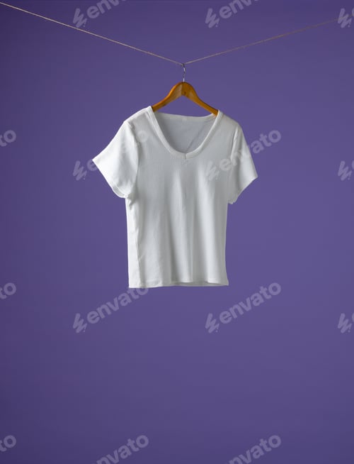 Preview: Tshirt hanging on coat hanger and copy space on purple background