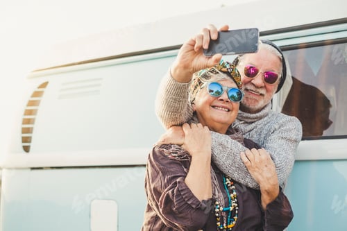 Preview: 70 years old cheerful happy adult couple take a selfie picture outside a vintage blue van