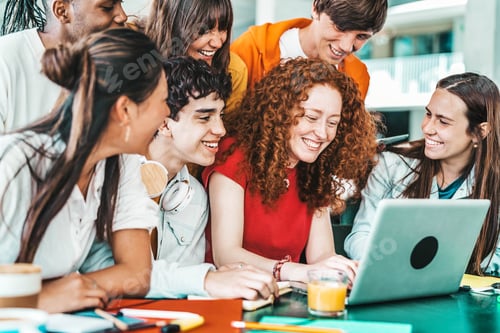 Preview: Multiracial university students sitting together at table with books and laptop