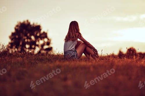 Preview: Silhouette Of A Woman Sitting On A Field.
