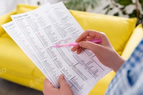 Preview: Cropped view of woman with pen holding allergy test results