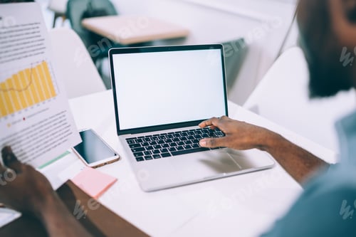 Preview: Man surfing on laptop and analyzing paper chart