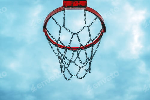 Preview: Low angle view of basketball ring and metal chain netting hoops against overcast sky in the evening