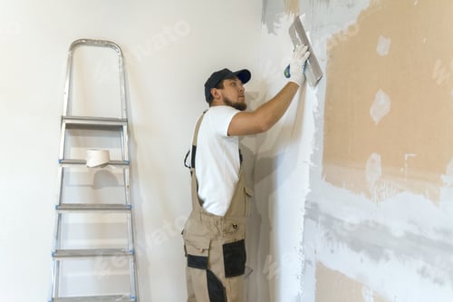 Preview: Male painter with a putty knife in his hands makes repairs in th