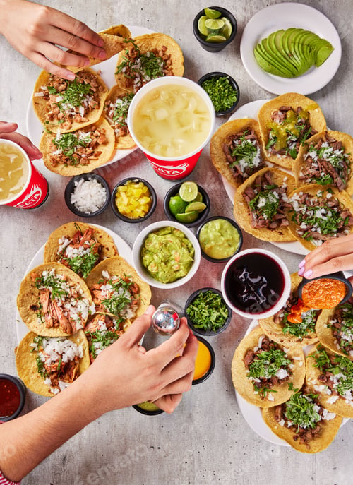 Preview: Vertical top view a gourmet dinner table with tacos and extra toppings