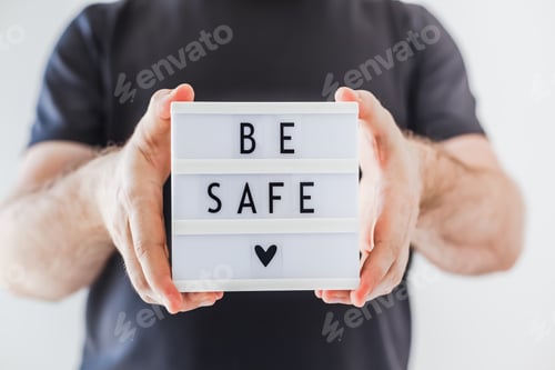 Preview: Man holding lightbox with text Be safe in his hand