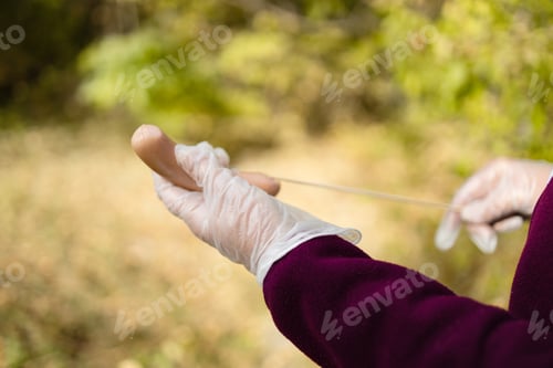 Preview: Female chef hand stringing raw sausage on skewer for cooking on fire at picnic