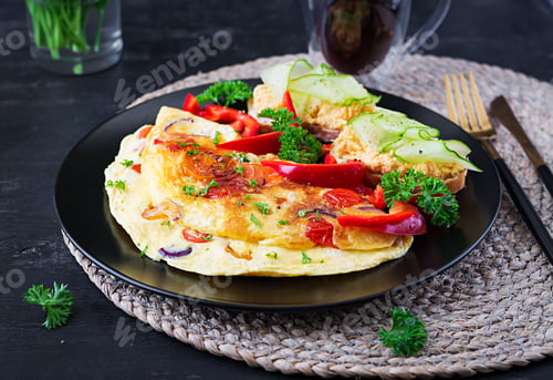 Preview: Omelette with paprika, cheese and tomatoes with sandwiches on black plate.