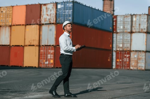 Preview: With digital tablet in hands. Male worker is on the location with containers