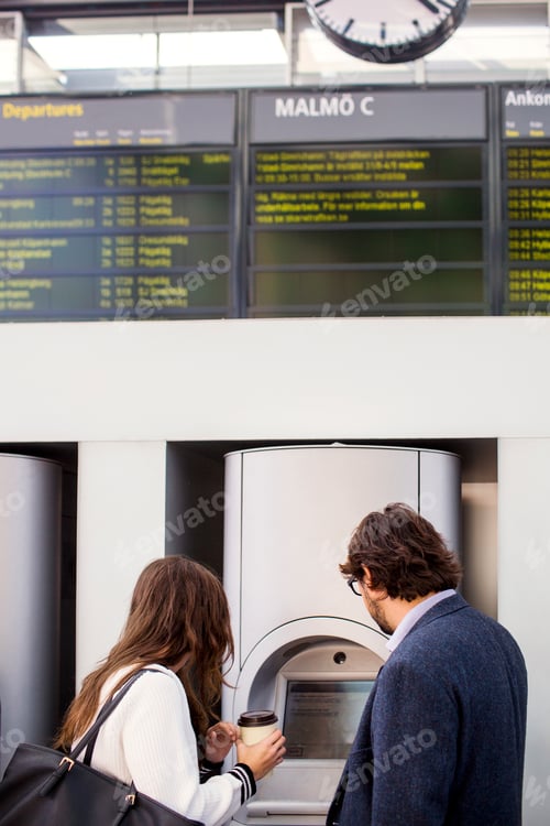 Preview: Side view of business colleagues using ticket machine at railroad station