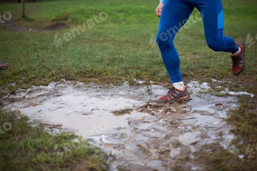 Preview: Legs of runner running through muddy puddle