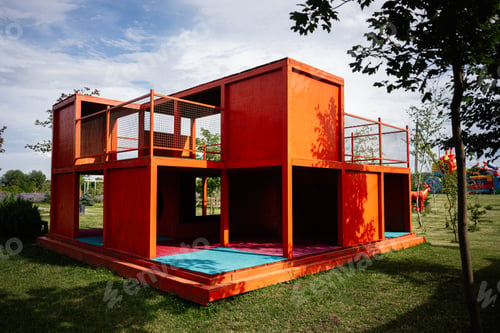 Preview: Bright orange playground structure in a park with vibrant colors and greenery.